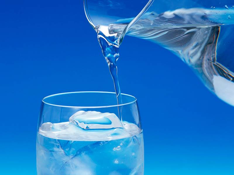 imagem de jarra com água colocando água límpida no copo de vidro